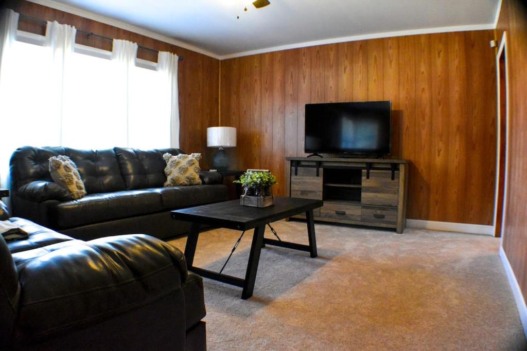 sala de estar con sofá de cuero y TV en Williamsburgh Place en Fayetteville