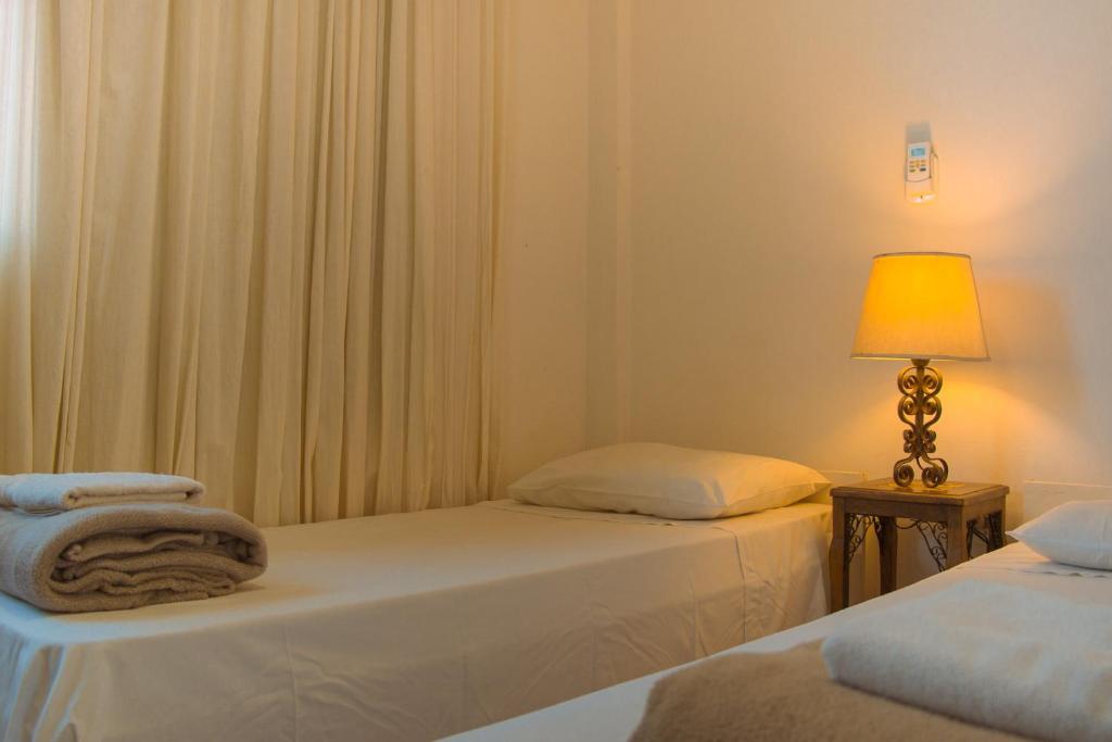 2 camas en una habitación con lámpara y cortinas en Hotel Solar dos Tchuccos, en Uruguaiana