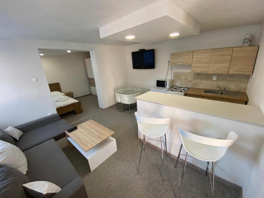 a kitchen and a living room with a counter and chairs at ARD Apartments - Levice in Levice