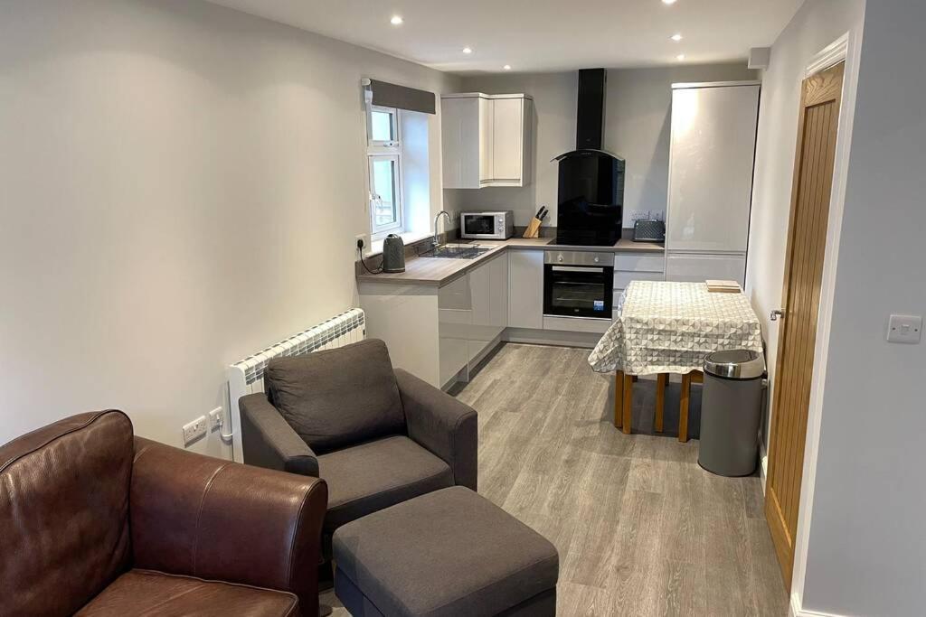 a living room with a couch and a chair and a kitchen at New apartment within short walk of the beach in Southbourne