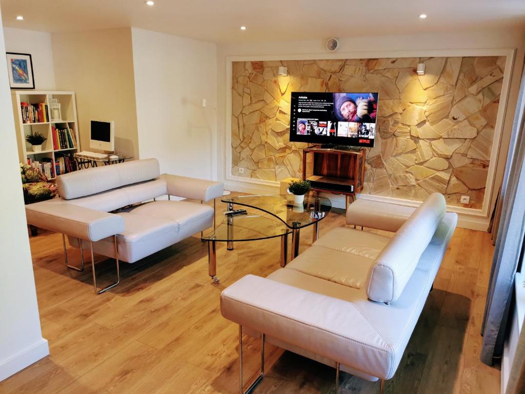 a living room with couches and a tv on a stone wall at APARTAMENT Olaf in Baryczka