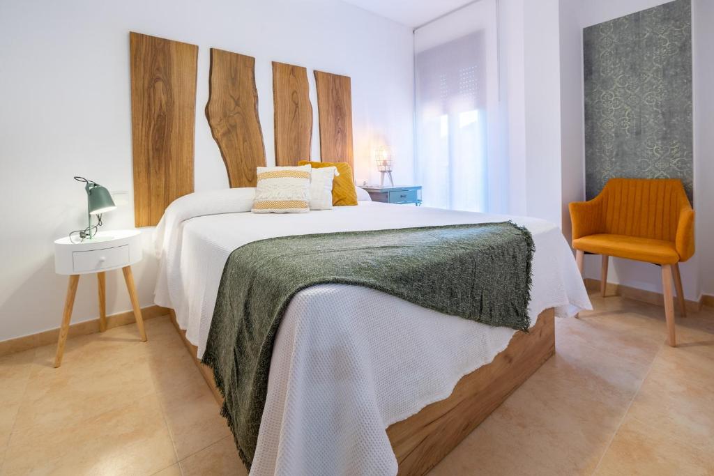 a bedroom with a large bed and a chair at Apartamento Boutique Plasencia Centro in Plasencia