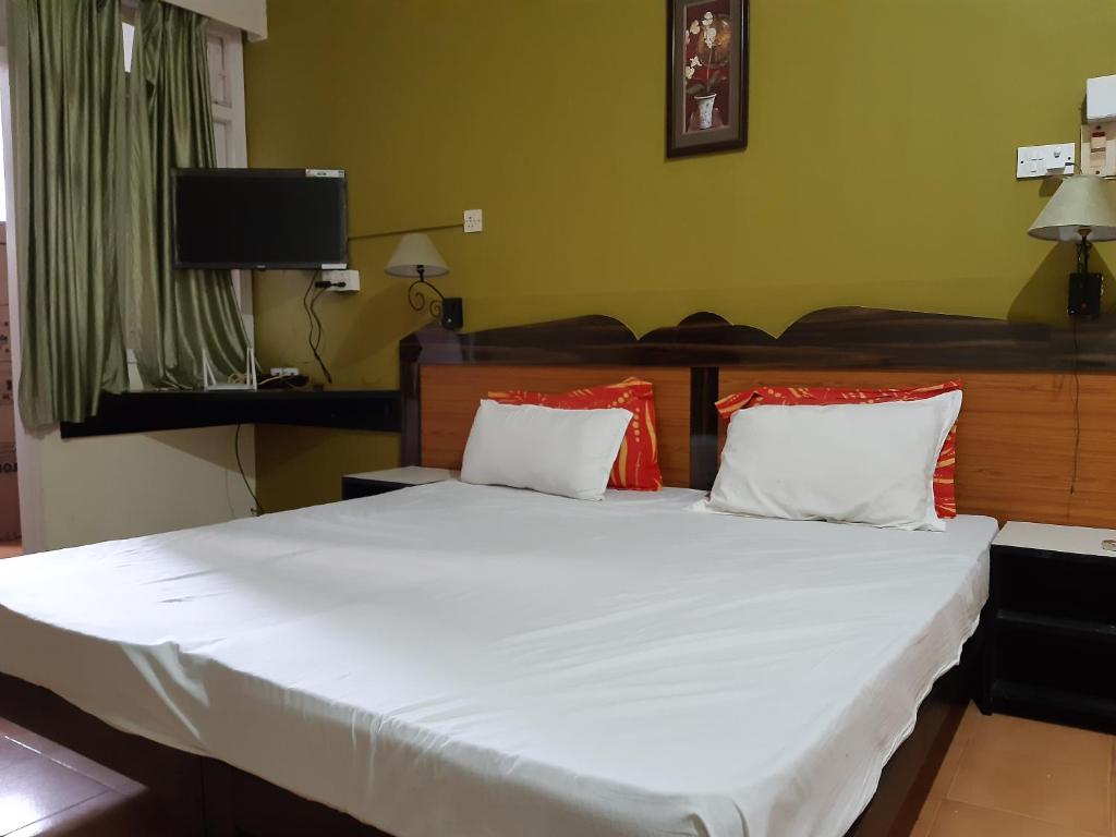a bedroom with a large white bed with red pillows at Palm Grove 1 Bhk Apartment at Candolim Beach with free Wifi in Candolim