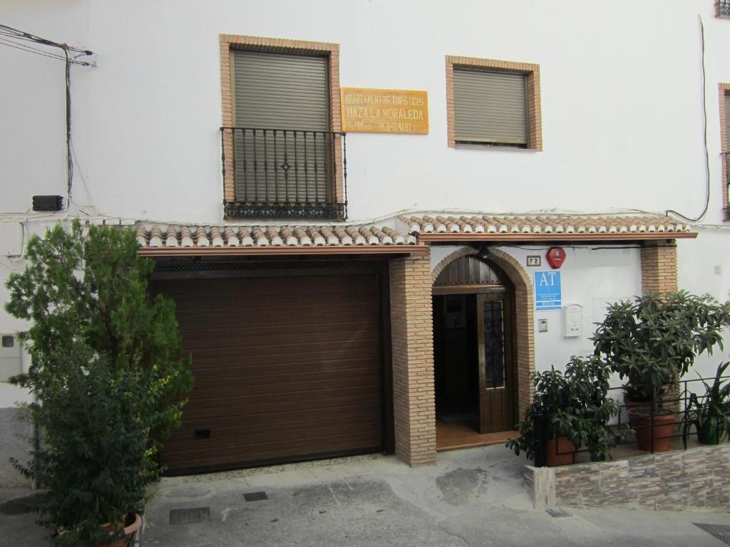 a building with a brown garage door and two plants at Apartamentos Haza La Moraleda in Güéjar-Sierra