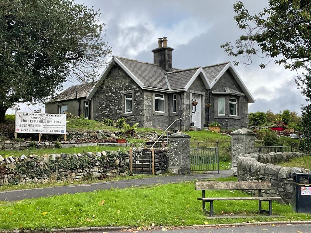 una casa in pietra con una panchina davanti di Modernised 1720s cottage Newton Stewart Scotland a Newton Stewart