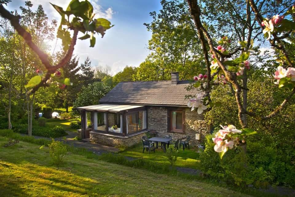 a small stone cottage with a picnic table in a garden at La Petite Maison in Six Planes