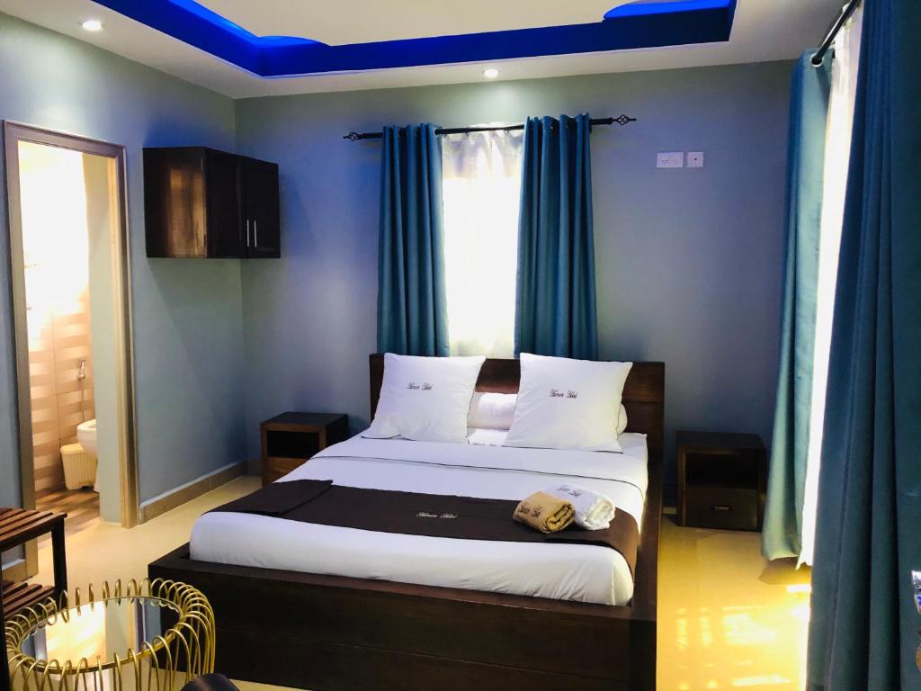 a bedroom with a bed with blue walls and blue curtains at Human hotel Ivato in Antananarivo