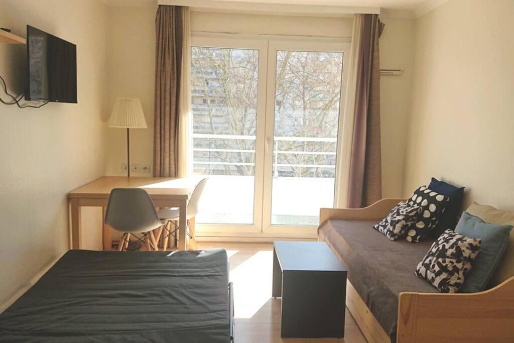 a living room with a couch and a table and a window at 7 min Walk Metro Line 1-La Defense Charras in Courbevoie