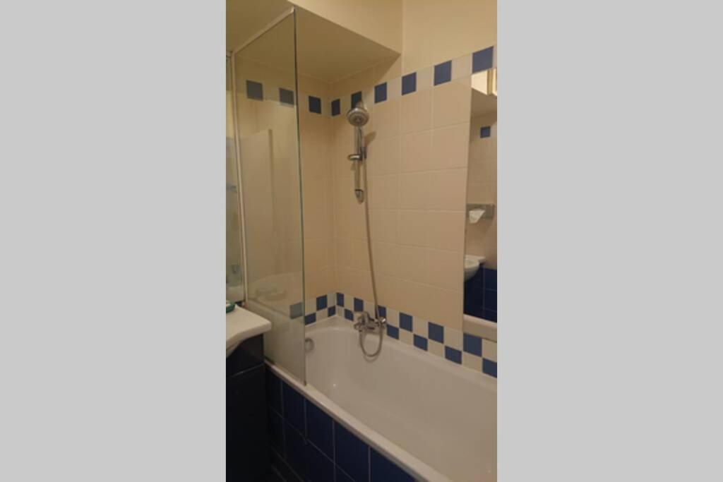 a bathroom with a tub and a shower with a mirror at 7 min Walk Metro Line 1-La Defense Charras in Courbevoie