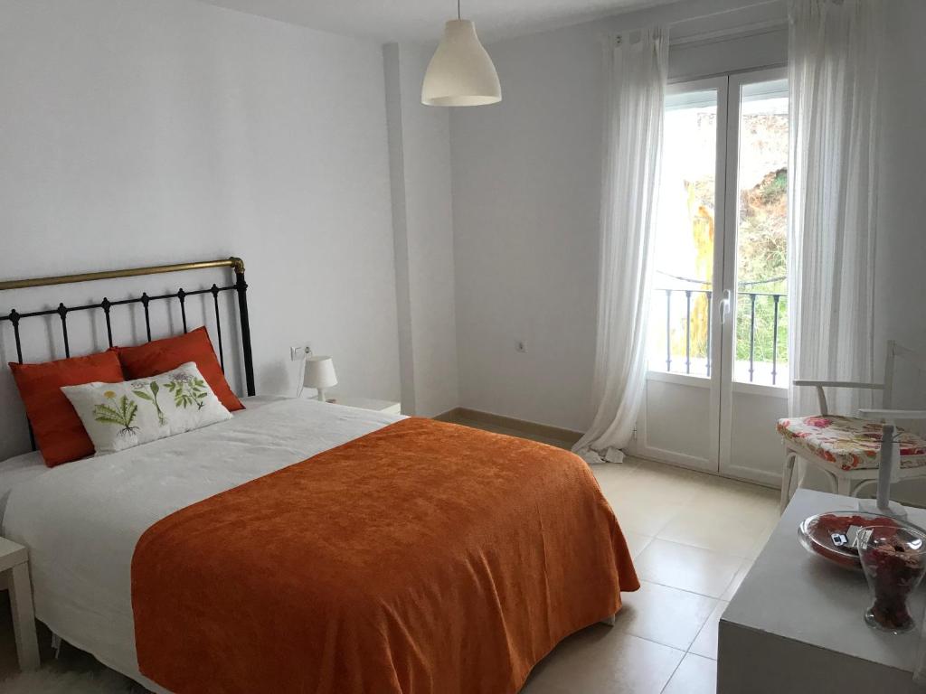 1 dormitorio con 1 cama grande con manta naranja en Casa COMPARTIDA Algarrobo, en Algodonales
