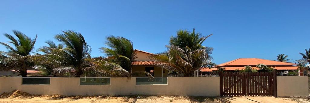 a house with palm trees behind a fence at Casa na Praia in Luis Correia