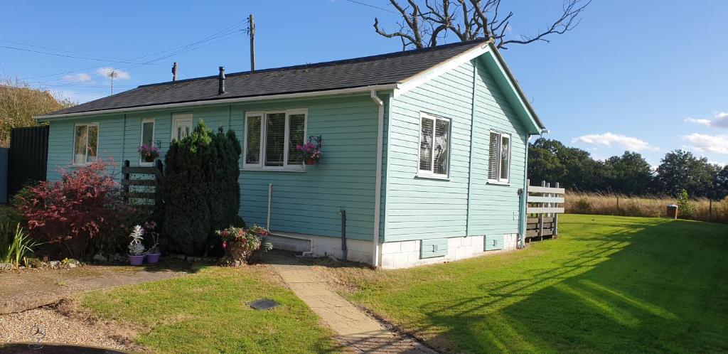 a small blue house with a grass yard at The Cabin,Kings Lane,Weston in Beccles