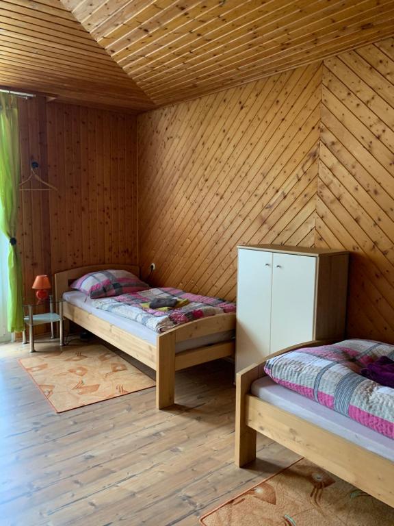 two beds in a room with wooden walls at Monteurwohnung Ahnetal mit 3 Schlafzimmern in Dörnberg