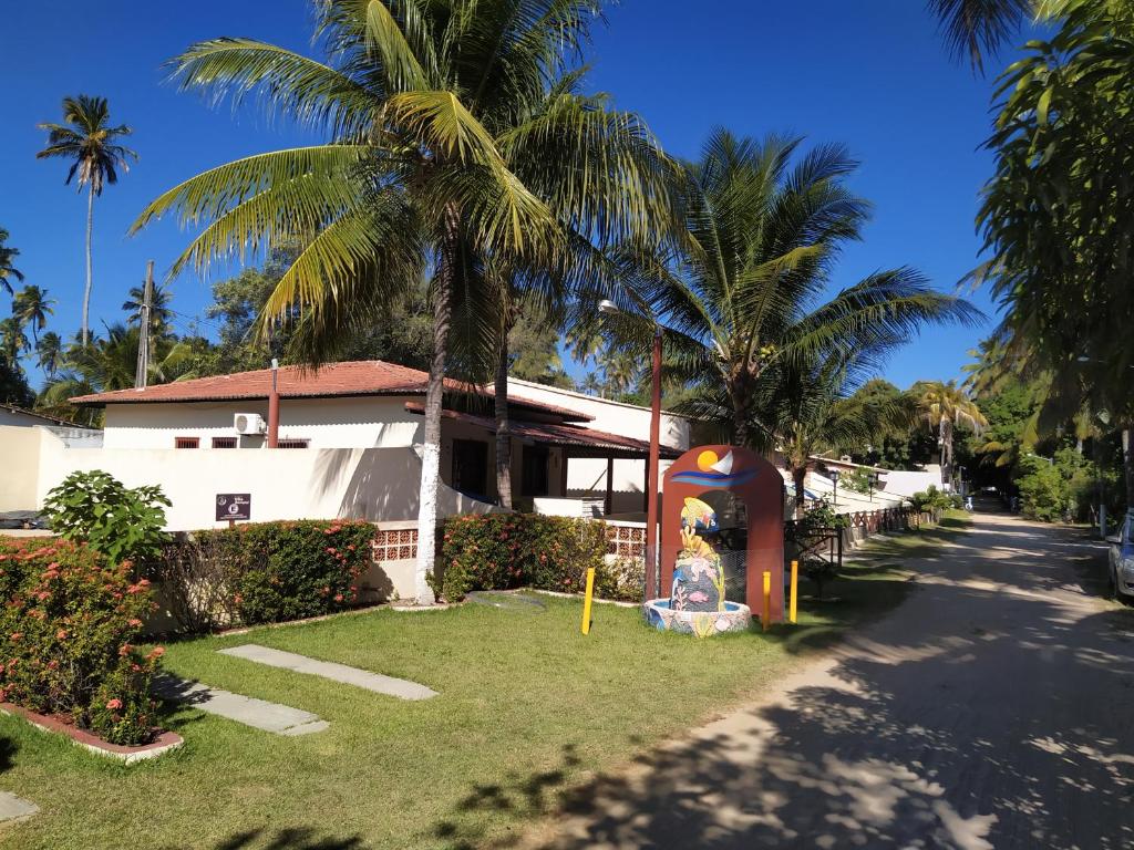 una casa con palmeras frente a un patio en Chalés Caribe brasileiro - Chalé 1, en Maragogi