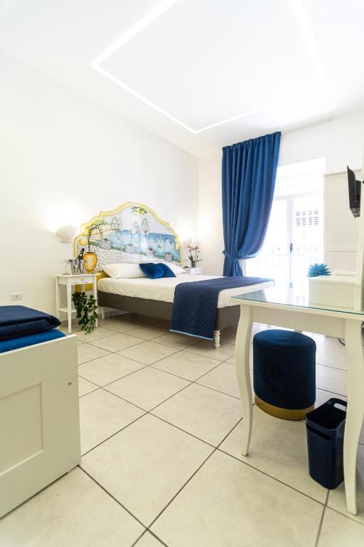 a bedroom with a bed and blue curtains and a desk at Biù b&b in Castellammare di Stabia