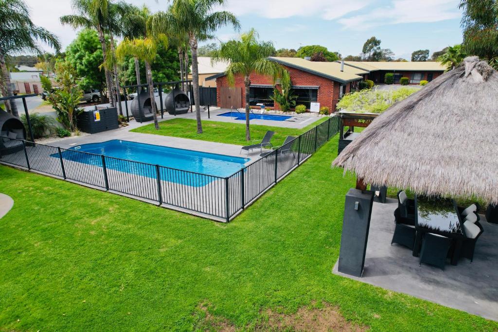 a backyard with a swimming pool and a thatch roof at Federation Motel Resort - Corowa in Corowa