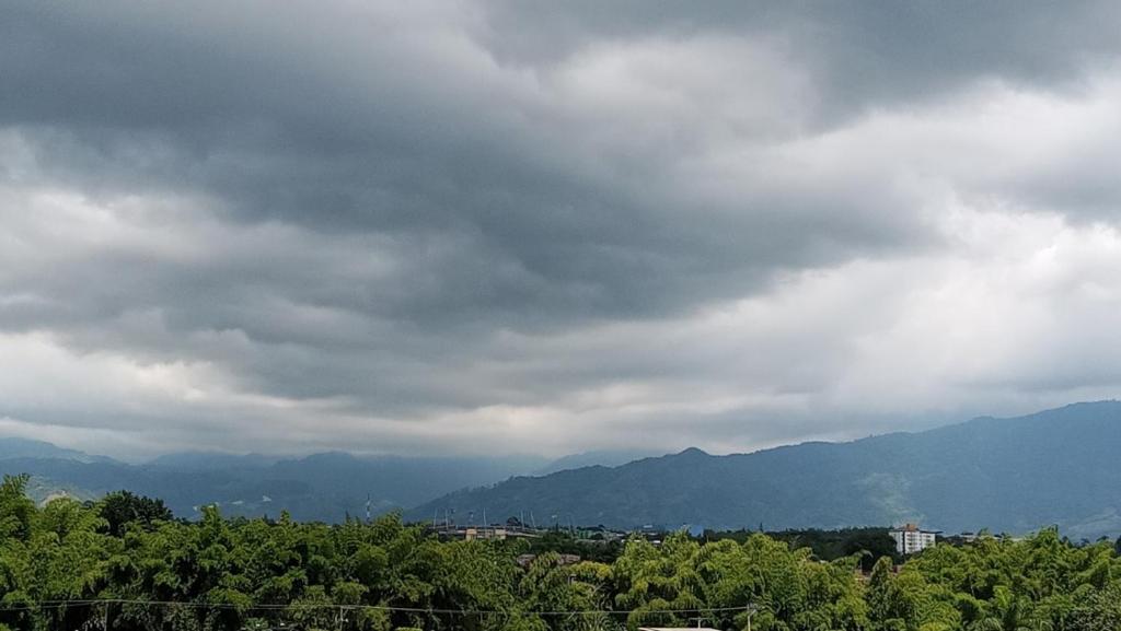 a cloudy sky with trees and mountains in the background at Acogedor Apartamento en Armenia, totalmente amoblado. in Armenia