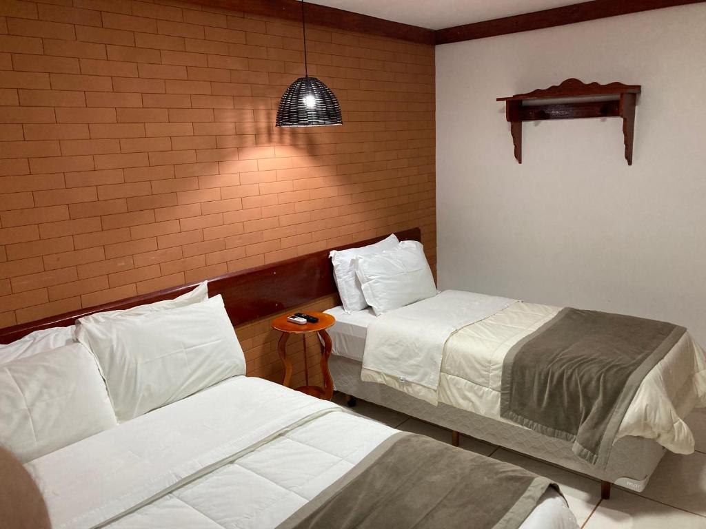 a hotel room with two beds and a lamp at Hotel Senador By Nobile in Quedas do Iguacu