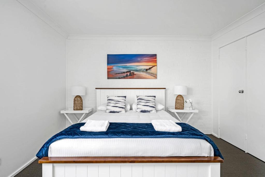 a white bedroom with a large bed with two pillows at Husky 56 Beachfront Villa's in Huskisson