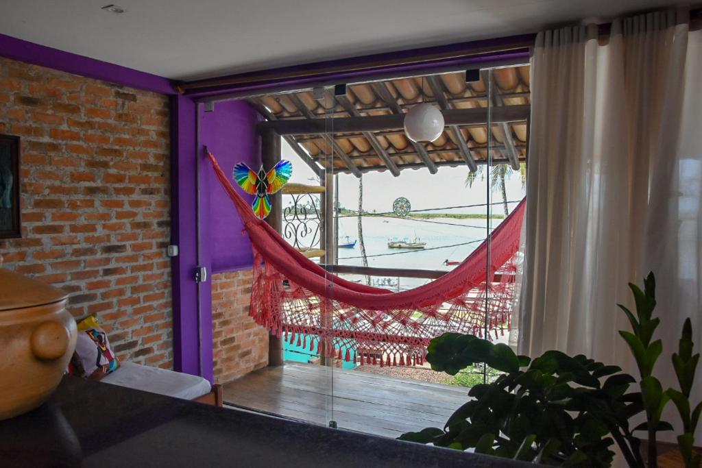 a room with a window with a hammock on a balcony at Casa Sol Nascente in Itacaré