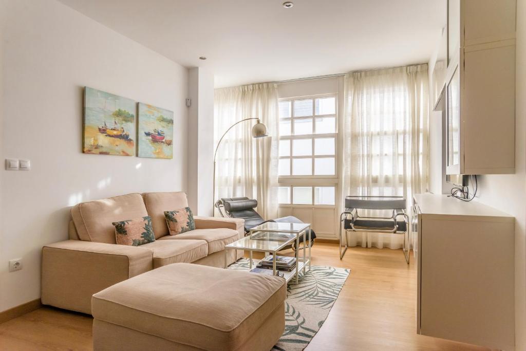 ein Wohnzimmer mit einem Sofa und einem Tisch in der Unterkunft Precioso apartamento nuevo en el centro de A Coruña! in A Coruña