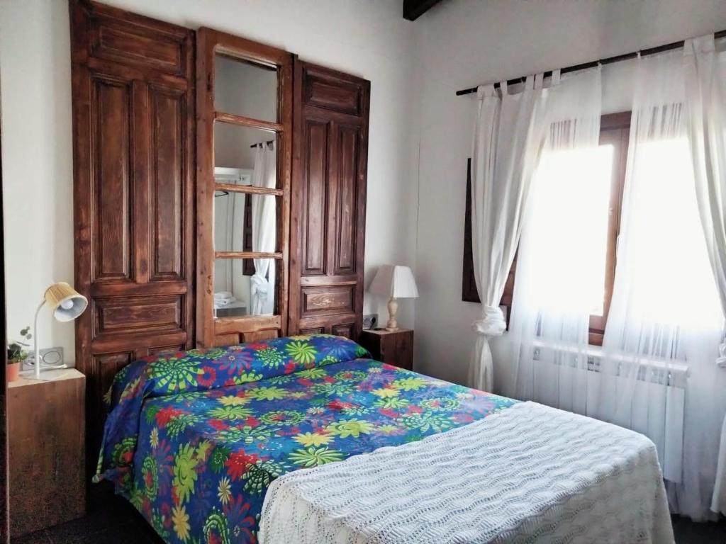 a bedroom with a bed with a wooden headboard and a window at En Huerto de Catalina in Fuentes de Béjar