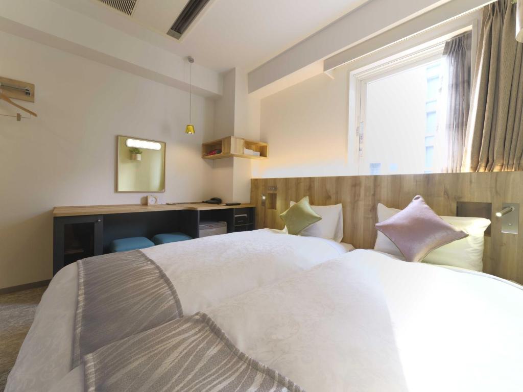 a bedroom with a large white bed and a window at Meitetsu Inn Nagoya Sakuradori in Nagoya
