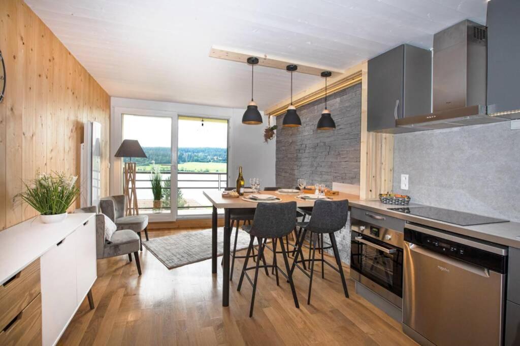 eine Küche mit einem Tisch und Stühlen im Zimmer in der Unterkunft Duplex La Vue du Lac in Malbuisson