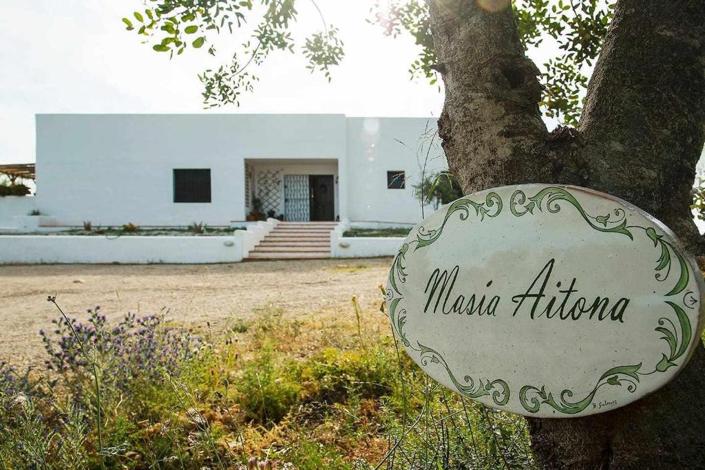 un cartel en un árbol delante de un edificio en Masía aitona tu rincón mediterráneo, en Useras