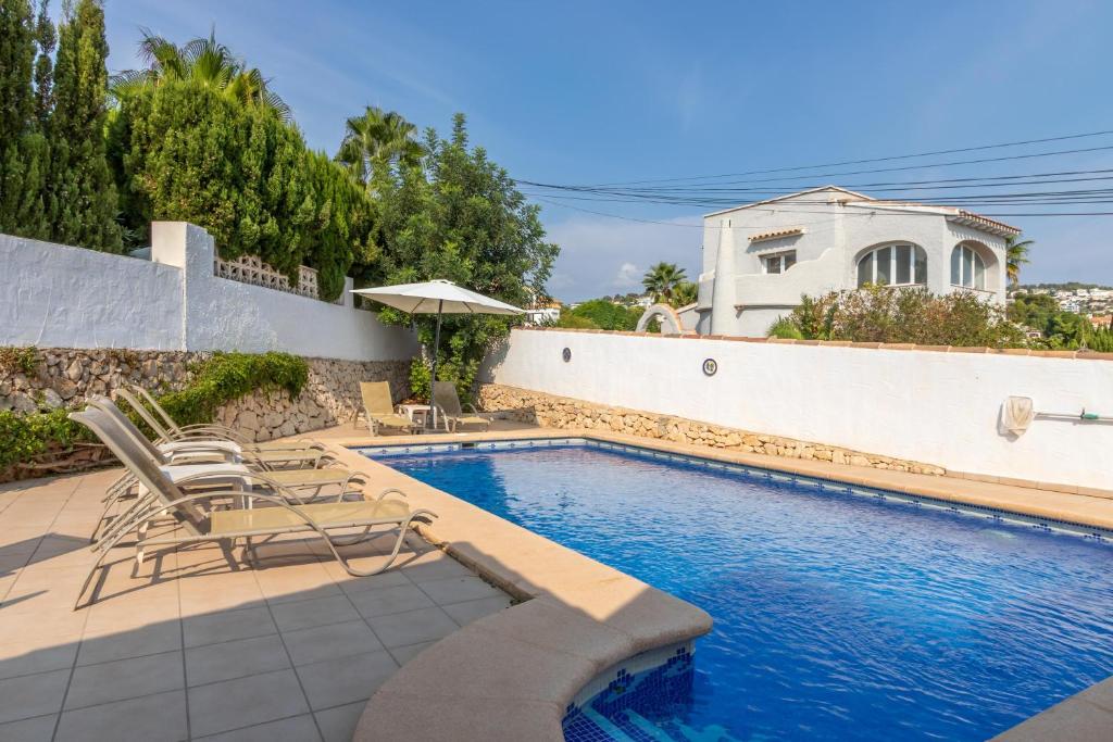 een zwembad met stoelen en een huis bij Villa Margarita in Casas de Torrat