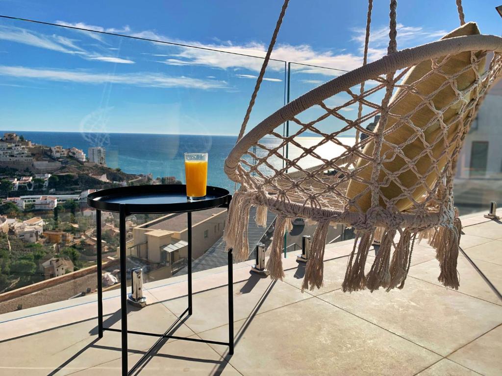 a glass of orange juice sitting on a table on a balcony at Colina del Sol Cullera - Villa Luna in Cullera