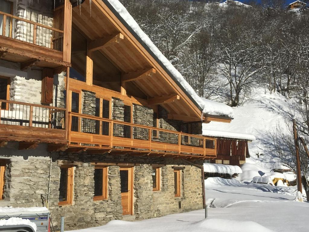 a log cabin with a deck in the snow at Chalet avec vue imprenable in Montvalezan