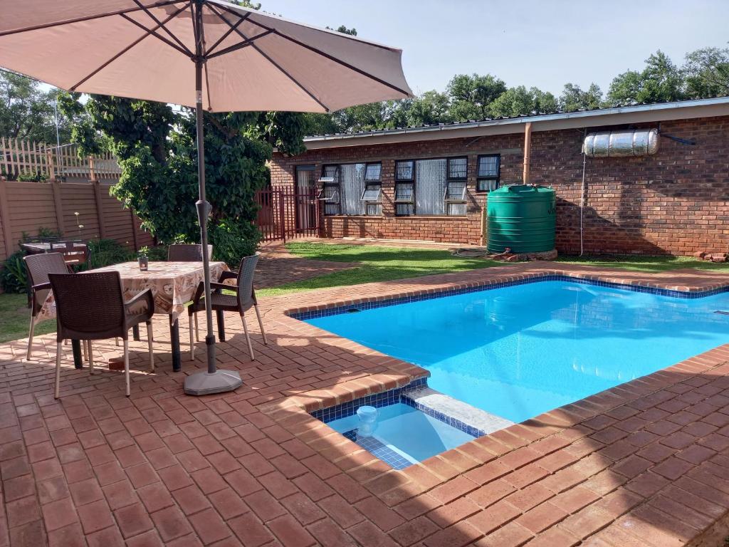 a table with an umbrella next to a swimming pool at White Rose Guest House in Vanderbijlpark