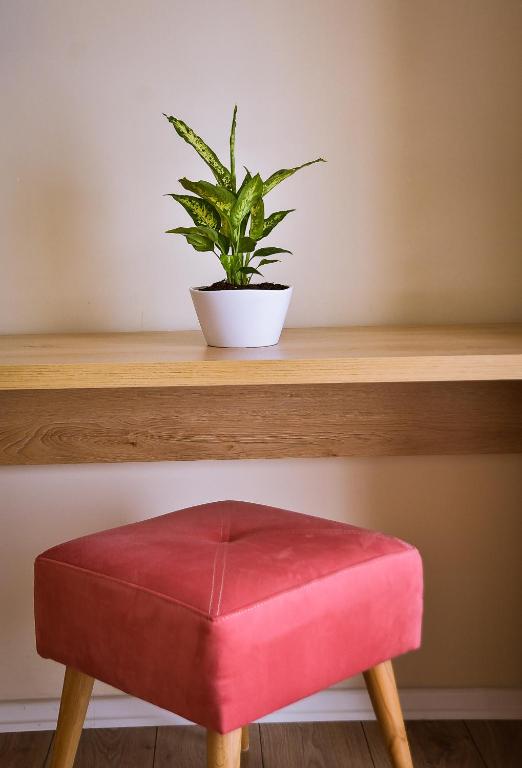 a red stool sitting on a wooden shelf with a plant at Airport Garden Hotel in Rinas