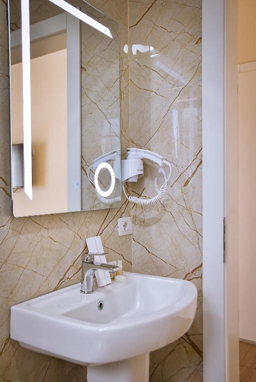 a bathroom with a white sink and a mirror at Airport Garden Hotel in Rinas