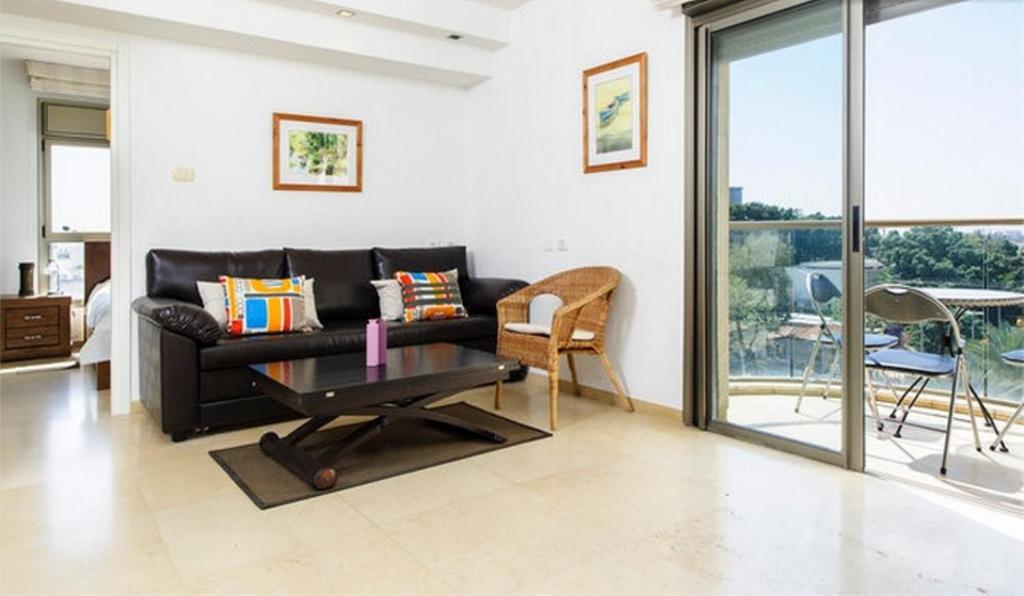 sala de estar con sofá negro y mesa en Holiday Raanana Apartments en Ra‘ananna
