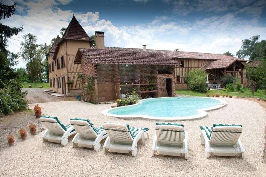 eine Gruppe von Stühlen und ein Pool vor einem Haus in der Unterkunft Domaine de la Source in Sainte-Christie-dʼArmagnac