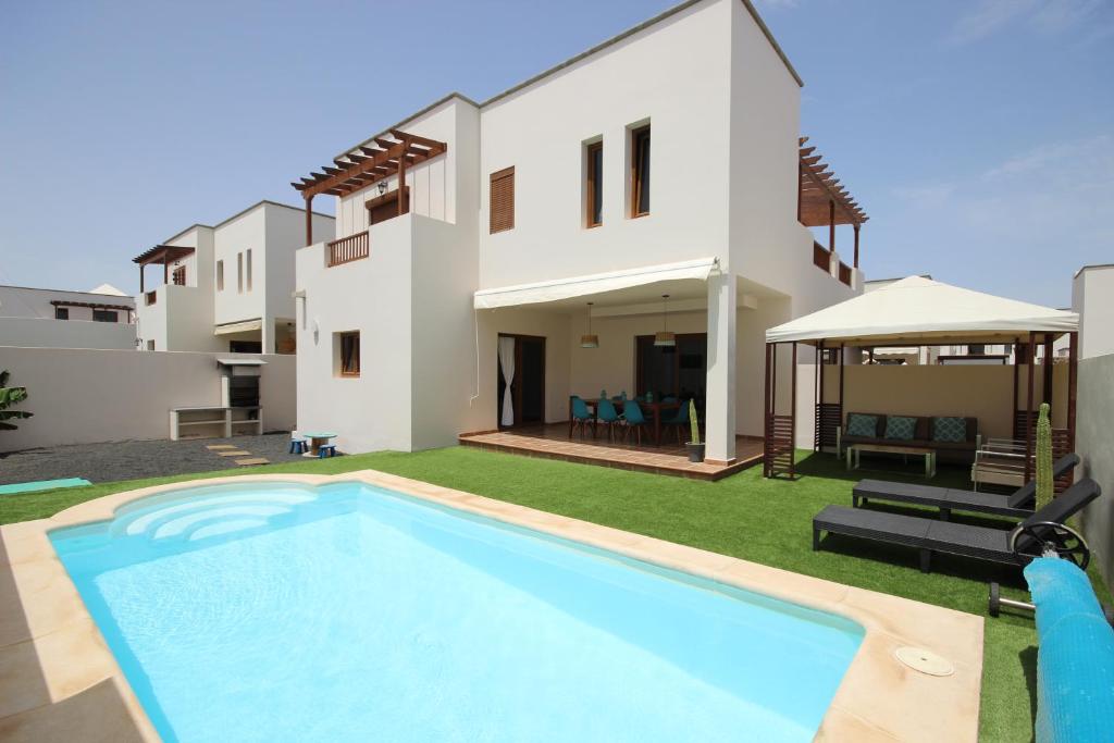 a villa with a swimming pool in front of a house at Villa Las Caletas del Mar - Heated Pool in Costa Teguise