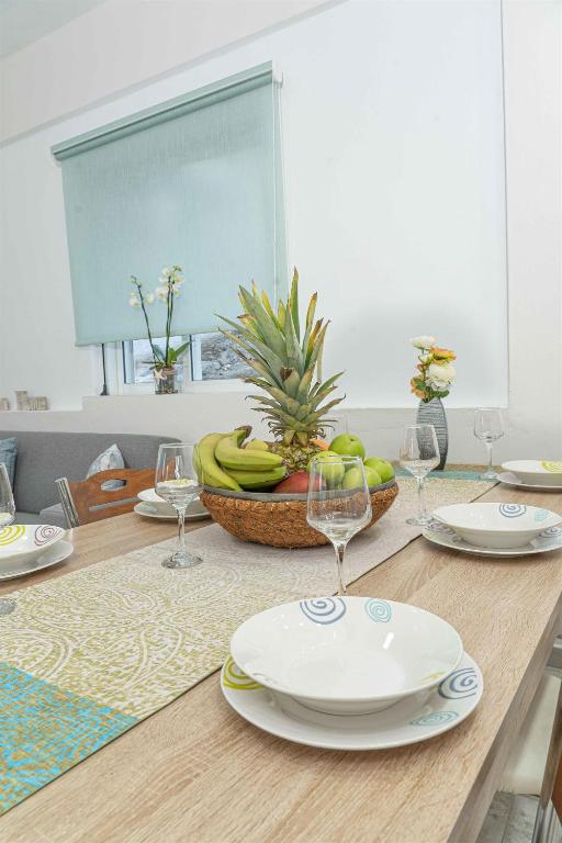 a table with plates and glasses and a bowl of bananas at Tzortzi's Family Apartments in Kaloi Limenes