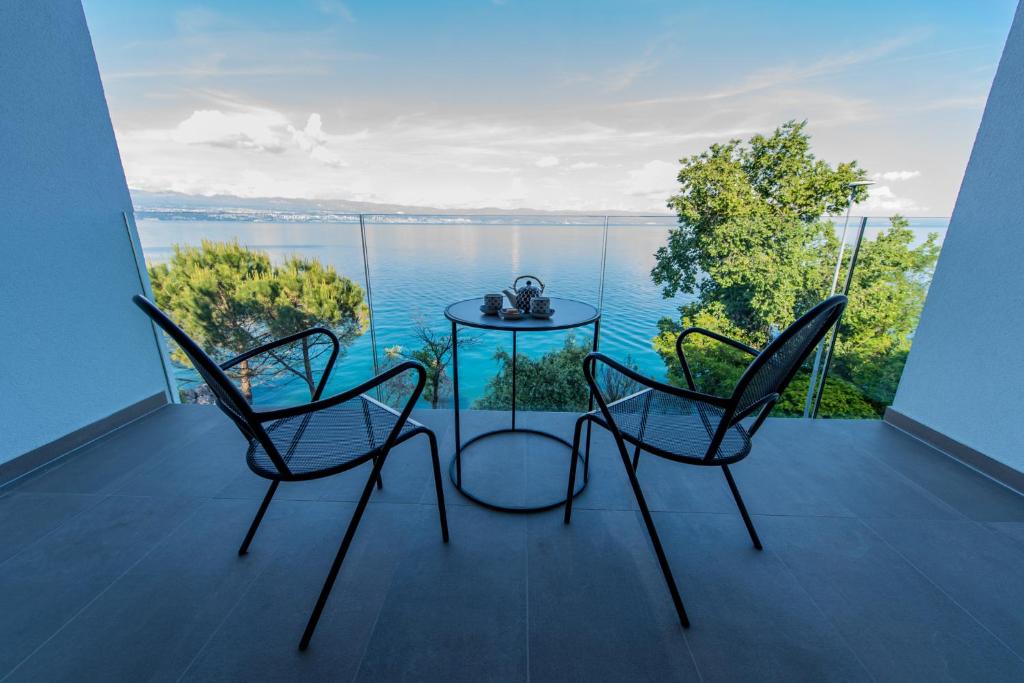 einen Tisch und Stühle auf einem Balkon mit Blick auf das Wasser in der Unterkunft Boutique Hotel Acacia in Lovran