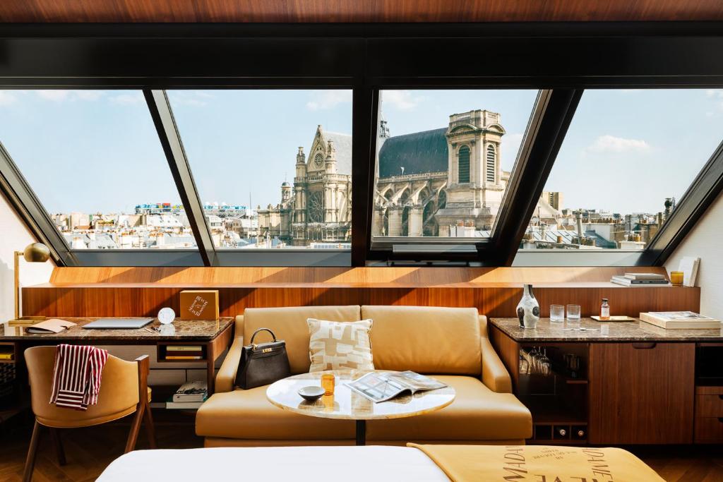 um quarto com um sofá e uma mesa e algumas janelas em Hôtel Madame Rêve em Paris