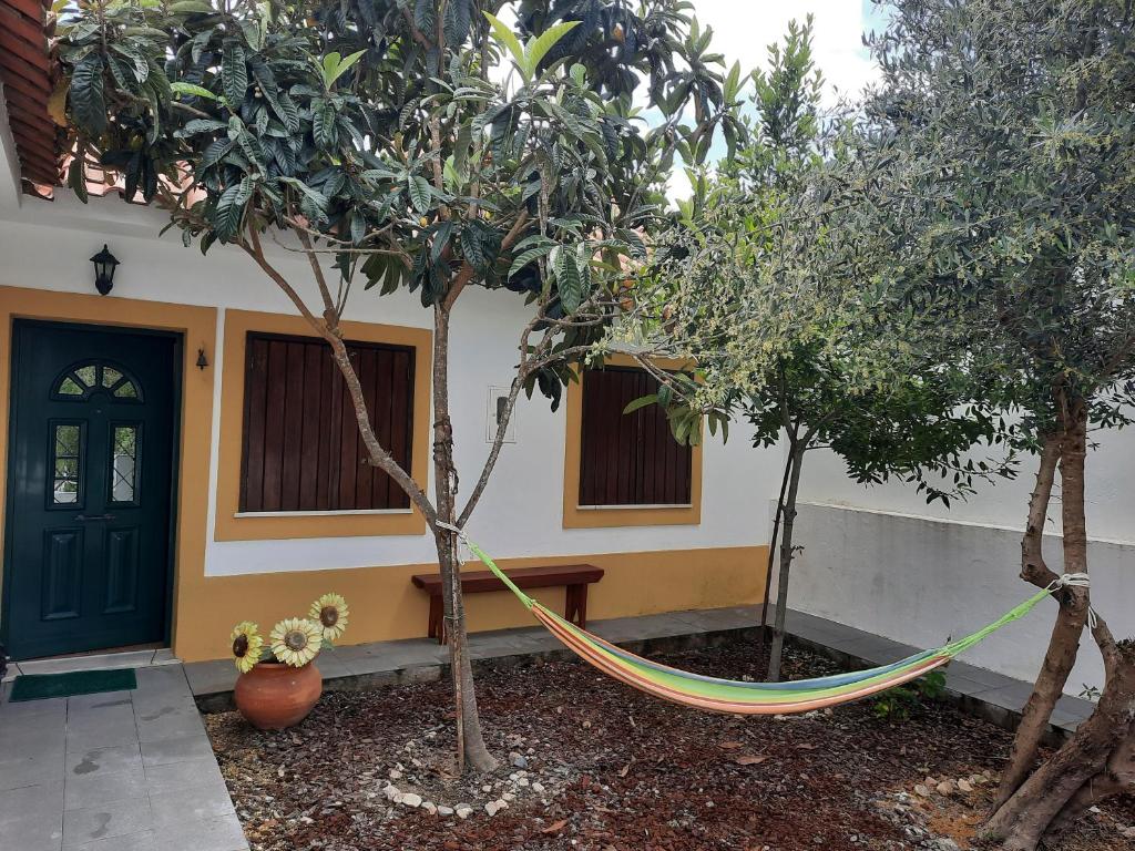 una hamaca entre dos árboles frente a una casa en Casa Zé Actor, en Cabeção