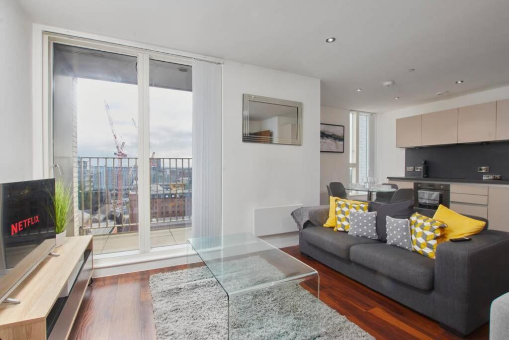 a living room with a couch and a large window at Lovely Apartment - Private Parking - Stadium Views in Manchester