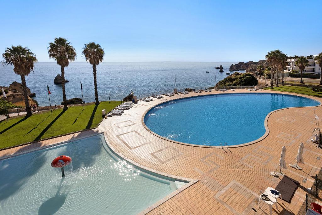 a large swimming pool with a view of the ocean at Apartamento Vista Mar in Lagos