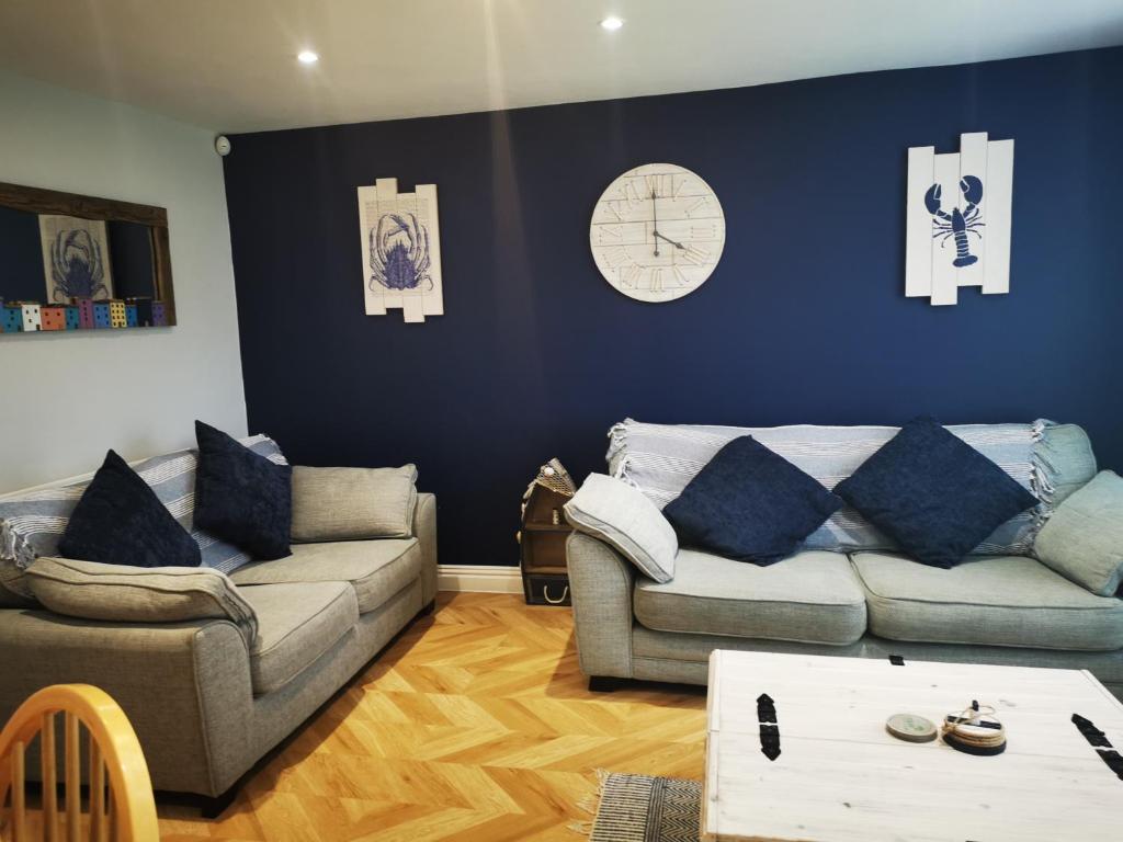 a living room with two couches and a clock on the wall at Tenby Flat in Pembrokeshire