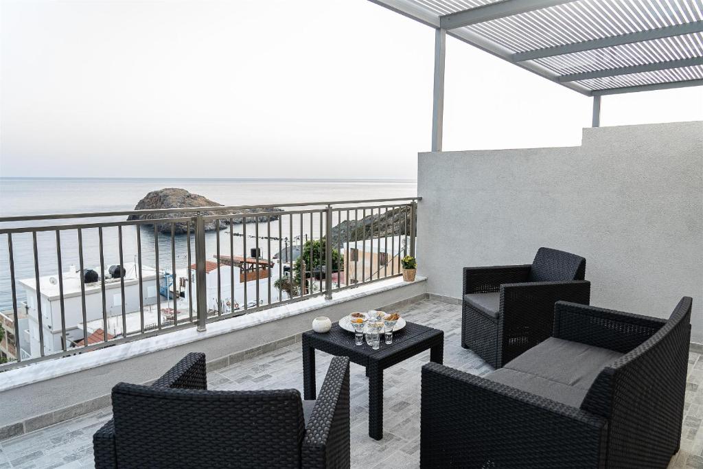 a balcony with chairs and a table and the ocean at Tzortzi's Family Apartments in Kaloi Limenes