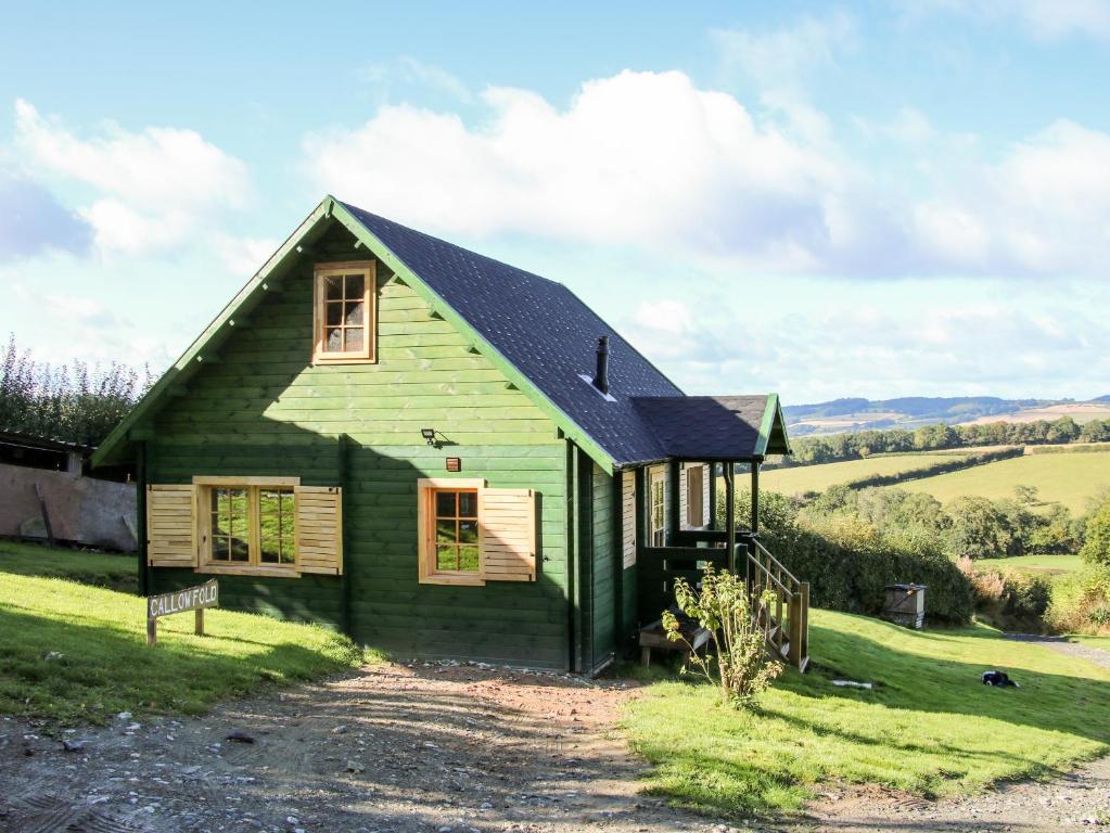 a green house with a black roof at Callow Fold in Craven Arms