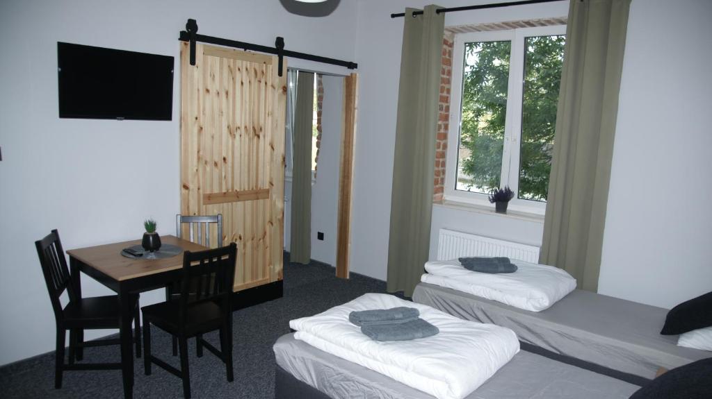um quarto com duas camas e uma mesa e uma mesa e cadeiras em Apartamenty Rycerskie em Inowłódz