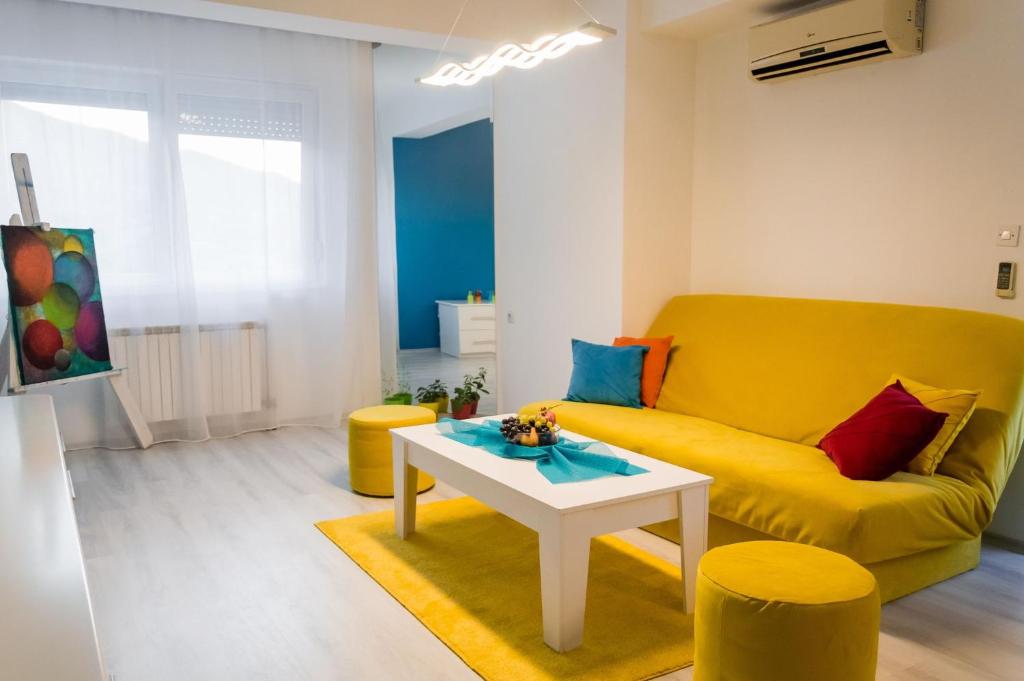 a living room with a yellow couch and a table at Aatma Apartment in Skopje