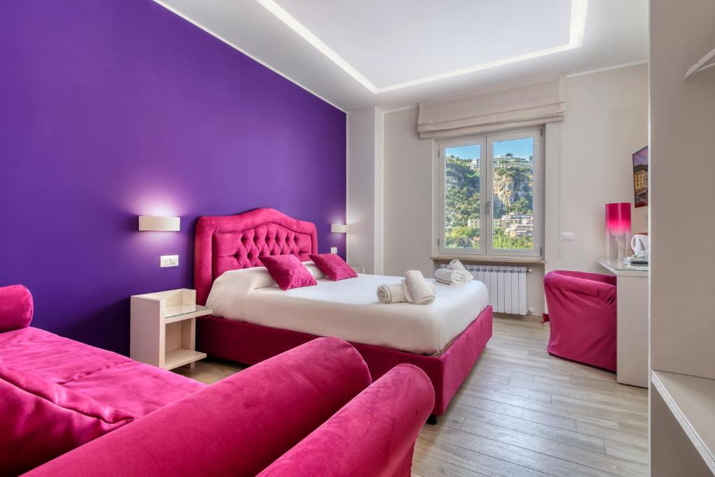 a purple bedroom with a bed and a couch at Tiffany Suites in Sorrento